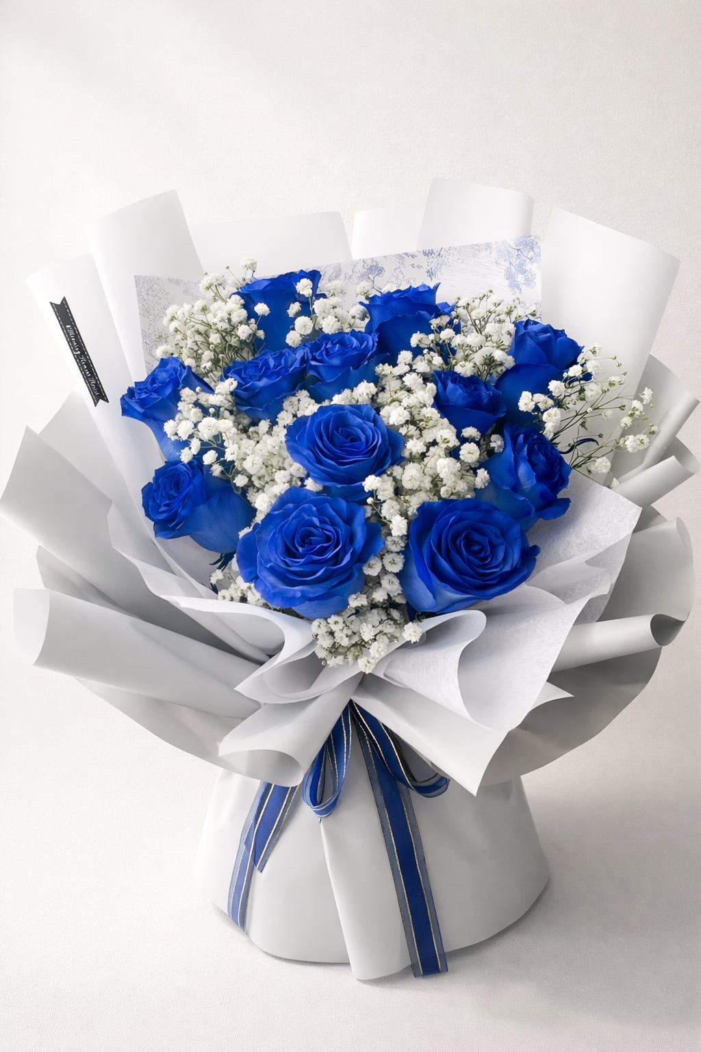 [FRESH FLOWER]  Elegant blue rose bouquet arrangement - A striking expression of elegance and charm, this bouquet features rich royal blue roses beautifully paired with delicate white baby’s breath. Wrapped in soft neutral-toned paper and finished with a refined ribbon, this design creates a perfect balance of bold color and graceful softness.  The deep blue roses symbolize mystery, uniqueness, and everlasting love, making this bouquet a meaningful gift for special moments—whether it’s a celebration, graduation, birthday, or a heartfelt gesture.  Designed in a modern Korean-style wrapping, this bouquet offers a clean, luxurious presentation that stands out effortlessly.