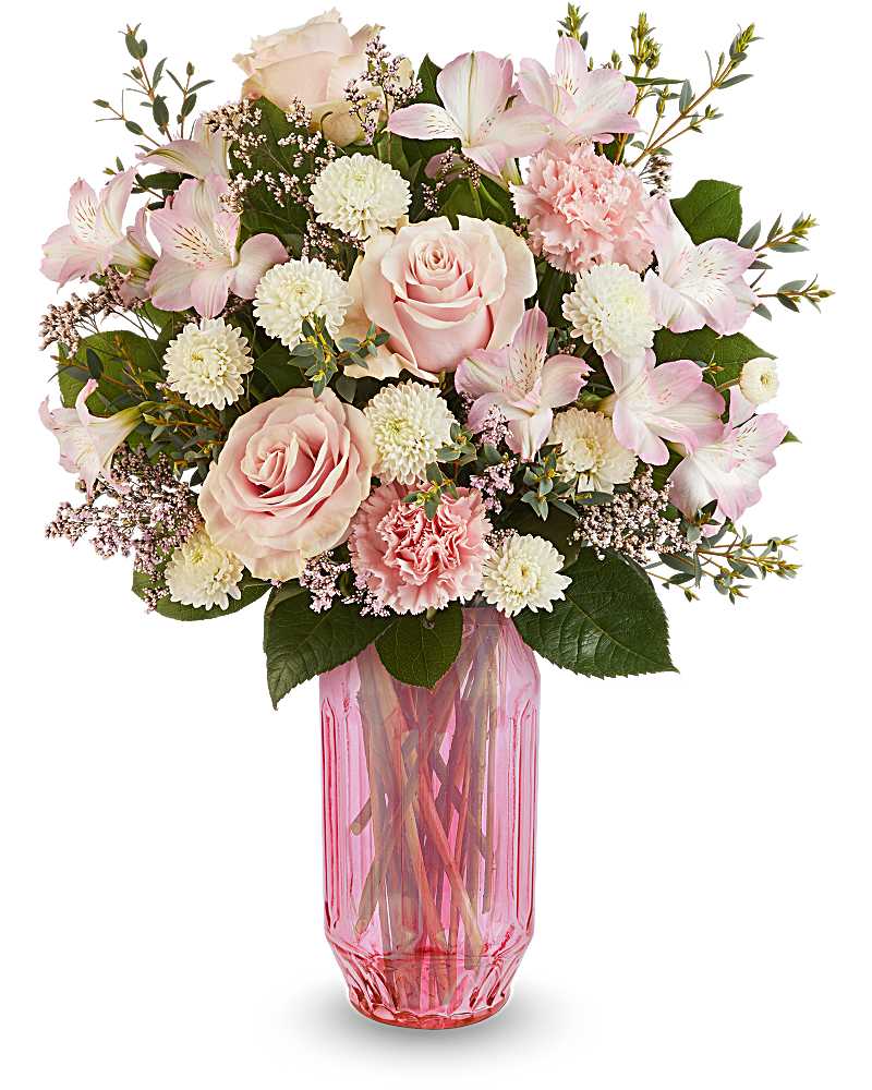 Arrangement of pale pink roses, carnations, and white mums in a tall pink glass vase