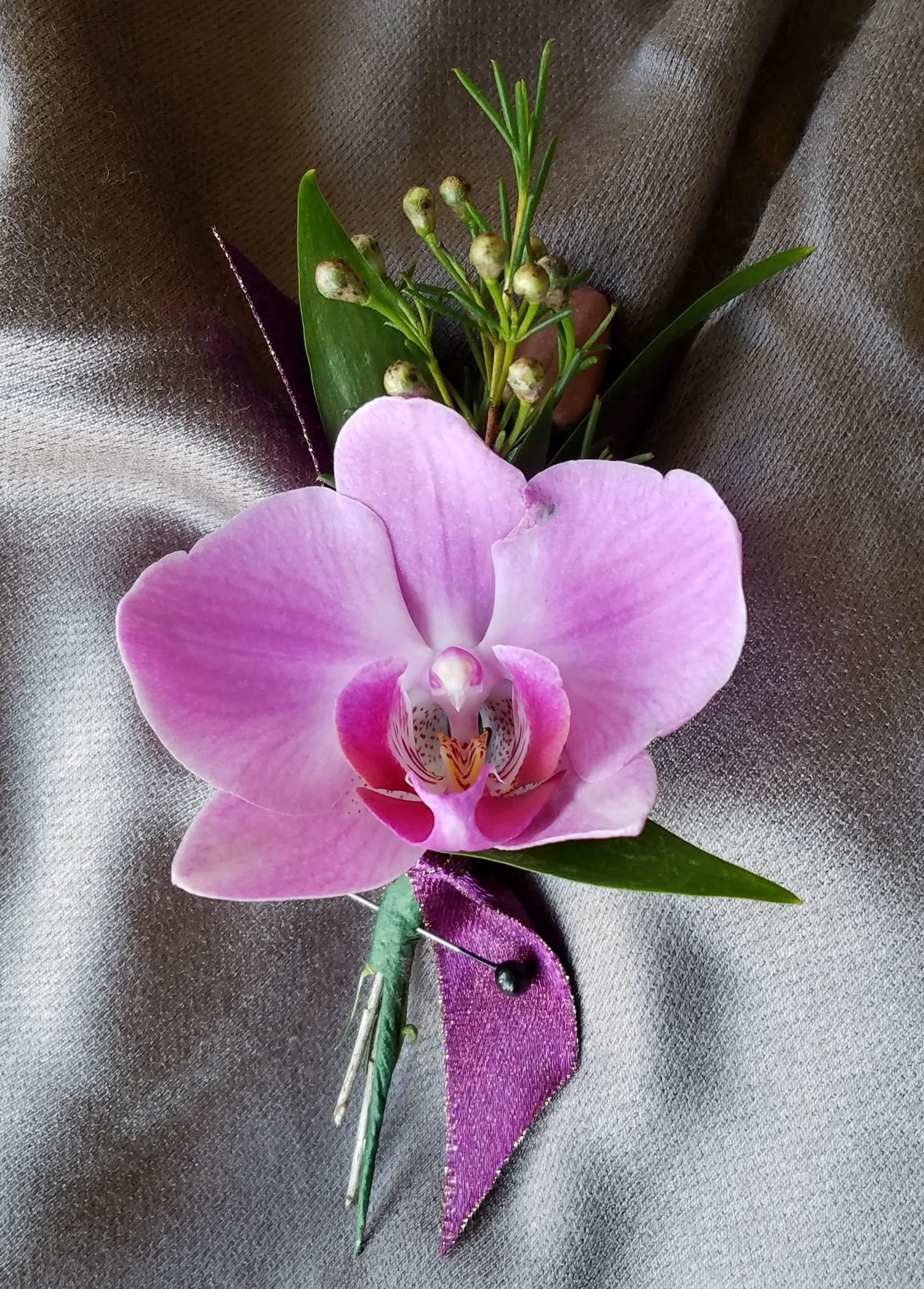 Boutonniere Orchid  - This Boutonniere has 1 orchid of common colors (white, pink, purple, green) with greens and filler. We have all sorts of ribbon from lime green sparkle to animal print, just tell us in the special instructions what your looking for! You may also send us a picture of the dress or inspirations to our email address lvfloral@gmail.com just make sure to include your name and order number.    ALL corsage/boutonniere orders will be ready for PICK UP ONLY between 12pm-4pm the day of the event. 