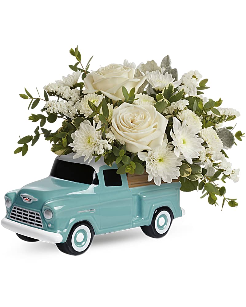 White roses and mums arranged in a light blue ceramic vintage truck container
