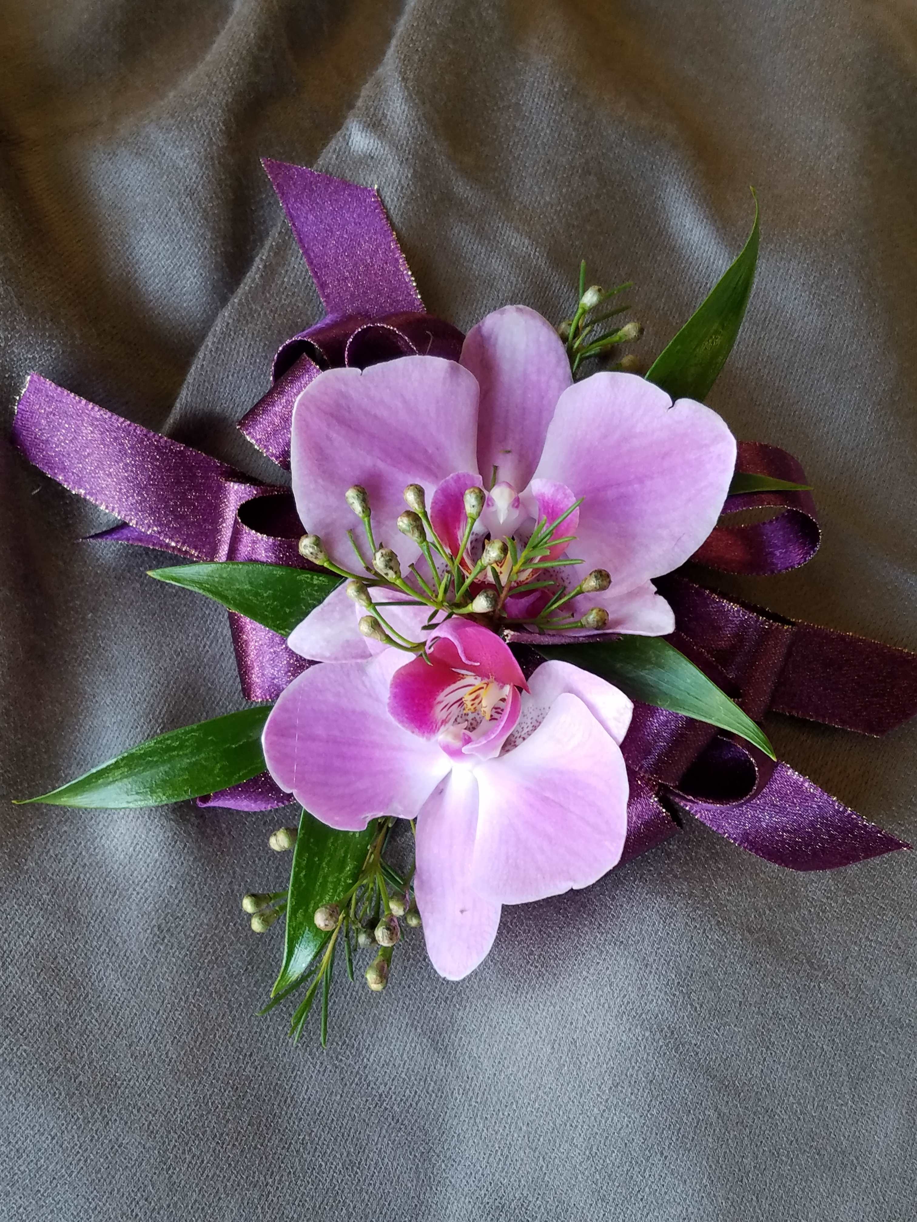 Corsage Orchid Standard - This corsage has 2 Orchids of common colors (white, pink, purple, green for orchids) with greens. We have all sorts of ribbon from lime green sparkle to animal print, just tell us in the special instructions what your looking for! You may also send us a picture of the dress or inspirations to our email address lvfloral@gmail.com just make sure to include your name and order number.    ALL corsage/boutonniere orders will be ready for PICK UP ONLY between 12pm-4pm the day of the event. 
