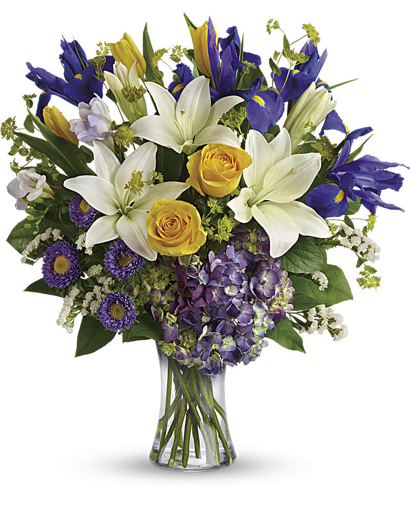 Mixed bouquet of white lilies, yellow roses, purple irises and hydrangea in a clear glass vase