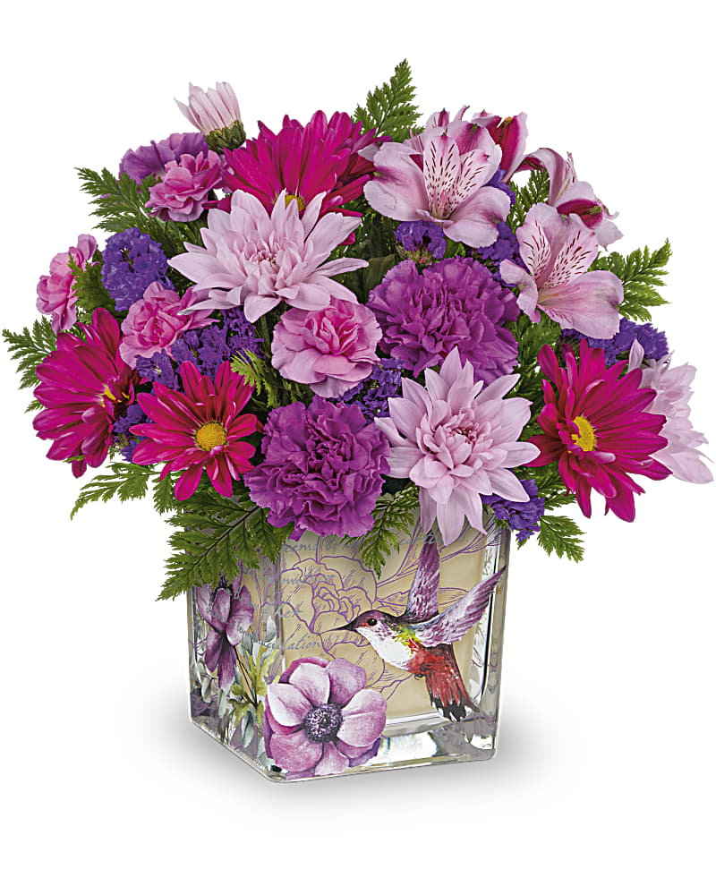 Pink and purple mixed flower arrangement in a square glass vase with a hummingbird illustration