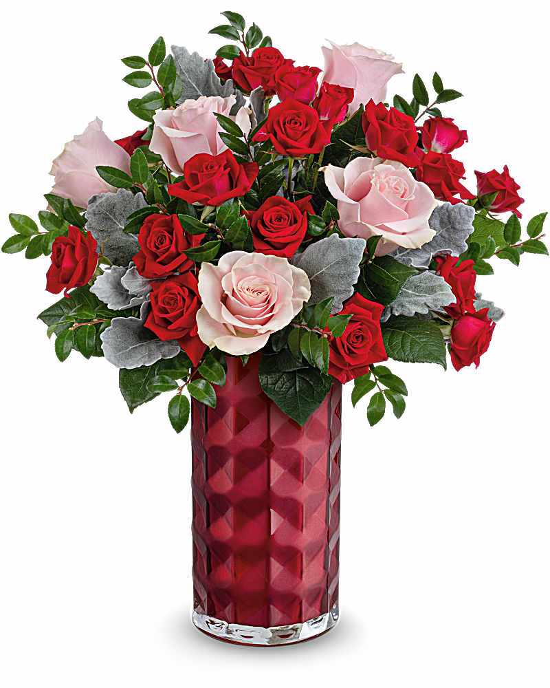 Tall red vase filled with red and pale pink roses accented with soft silver foliage.