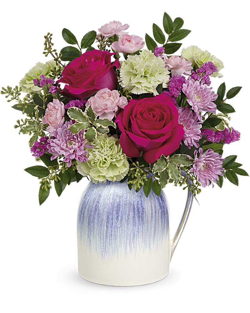 Arrangement of hot pink roses, green carnations, and pink mums in a blue and white ceramic pitcher.