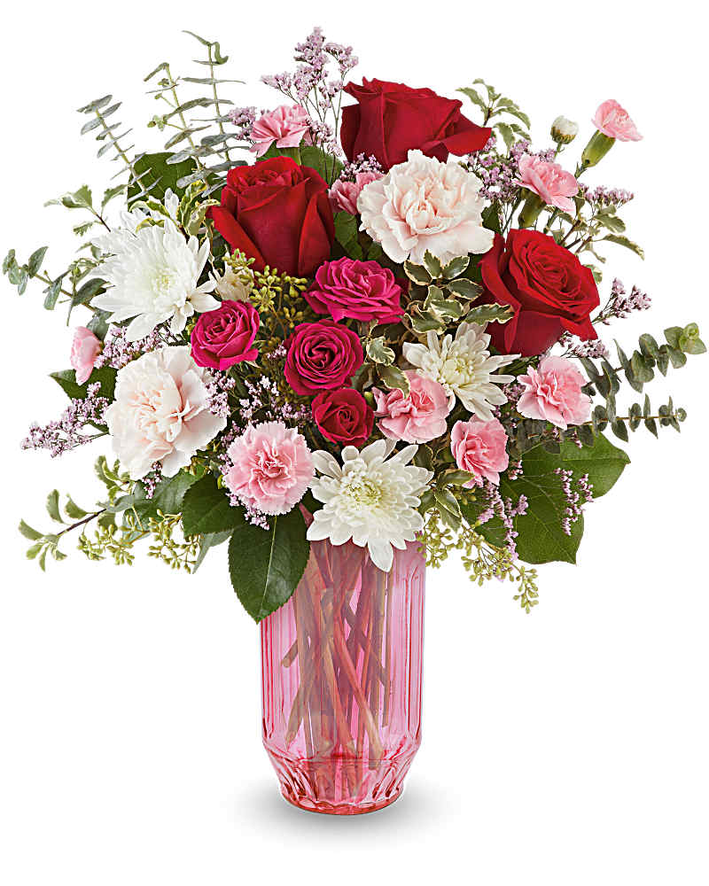 Arrangement of red roses, pink carnations, and white mums in a tall pink glass vase