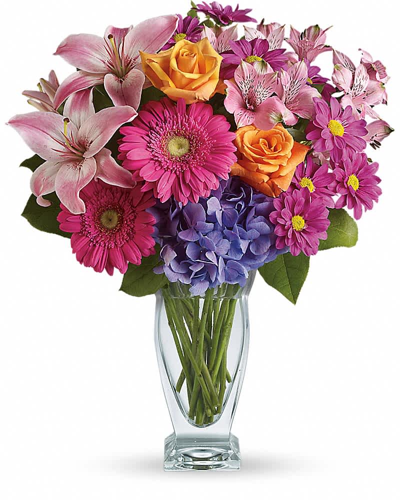 Mixed bouquet of pink lilies, gerberas, orange roses and purple hydrangea in a clear glass vase