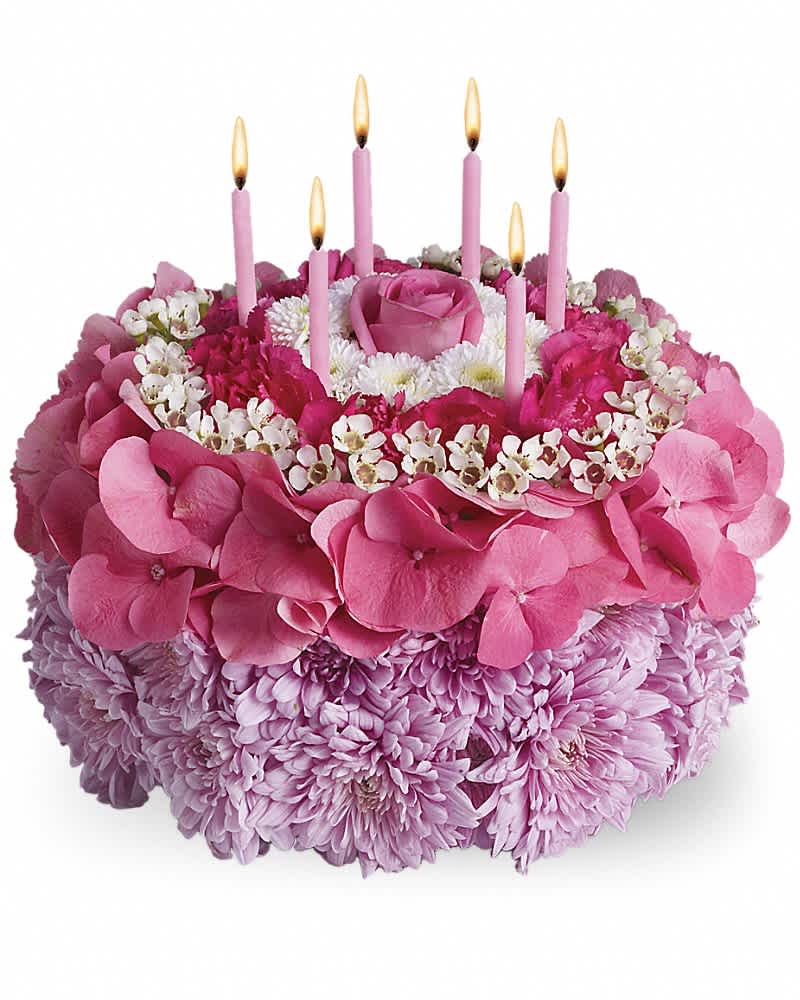 Round pink floral cake arrangement with candles made of roses, hydrangeas, and mums.