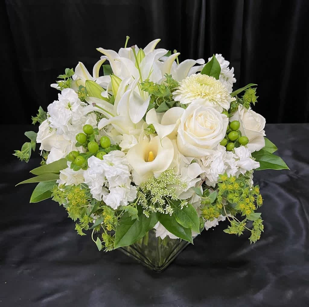 White lilies, roses, and calla lilies in a glass vase