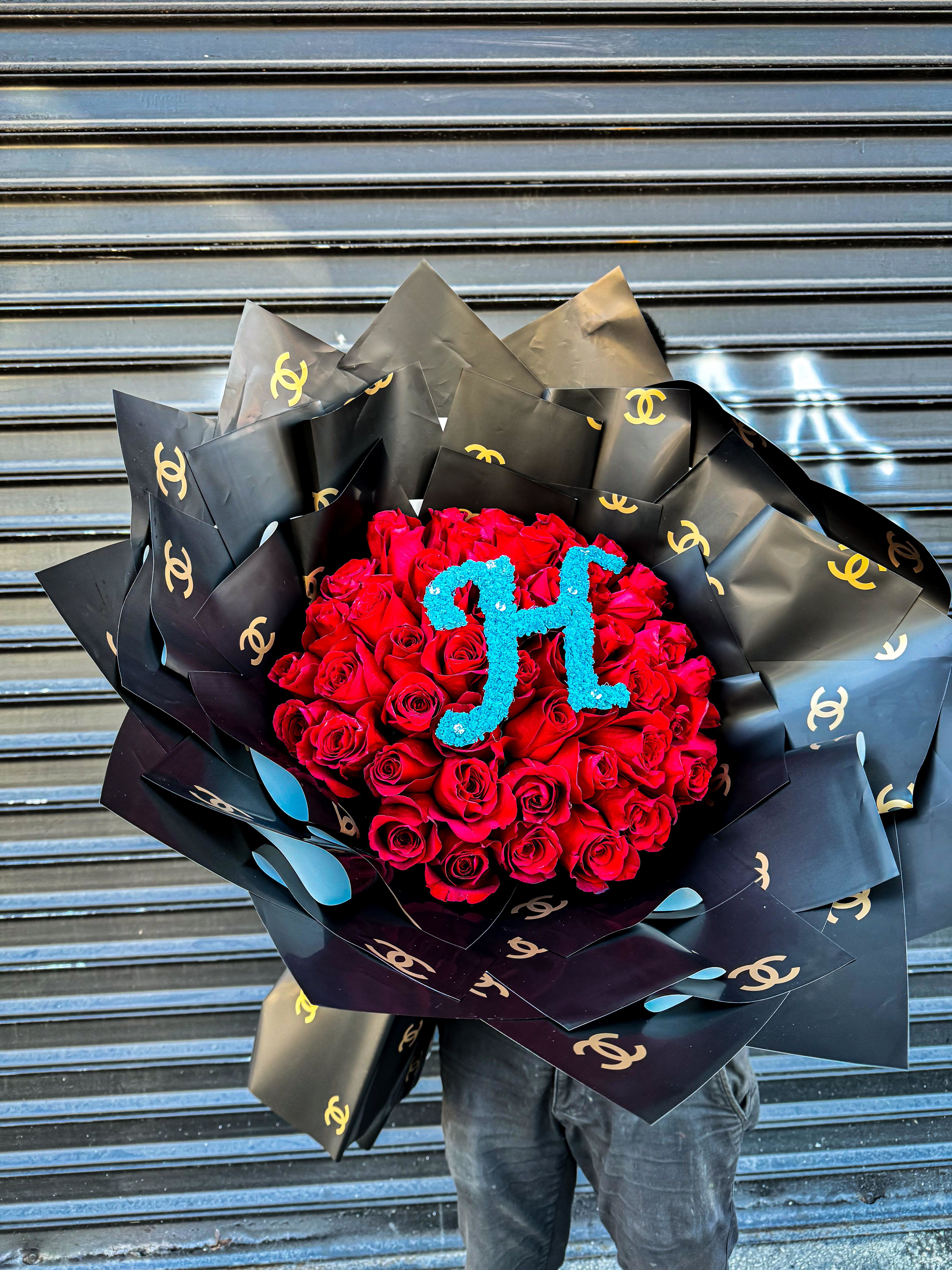 Large bouquet of red roses with blue monogram, wrapped in black logo paper