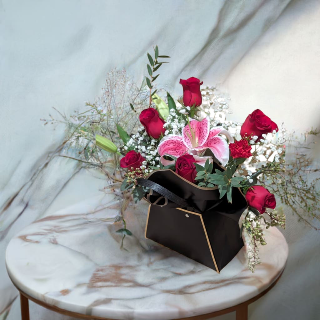 Stunning Beauty Valentine’s Bloom Bag - Make a bold, sophisticated statement this Valentine’s Day with the Stunning Beauty Valentine’s Bloom Bag. This chic and modern arrangement features lush red roses, vibrant pink stargazer lilies, and delicate baby’s breath, accented with fresh seasonal greenery for a touch of natural elegance.  What sets this arrangement apart is its unique luxury black bloom bag, accented with sleek gold trim and stylish handles, giving it a high-fashion, boutique feel. It’s not just a bouquet; it’s a work of art—perfect for someone with a taste for the extraordinary.  Why It’s Perfect for Valentine’s Day:  Red Roses: The ultimate symbol of love, passion, and romance.  Pink Stargazer Lily: Adds an exotic flair with its vibrant color and stunning fragrance.  Baby’s Breath &amp; Greenery: Softens the arrangement with delicate, ethereal beauty.  Luxury Bloom Bag: A stylish, reusable design that doubles as a decorative statement piece.  Modern Elegance: A perfect gift for trendsetters who appreciate contemporary aesthetics. Surprise your Valentine with the Stunning Beauty Bloom Bag—a gift that’s as fashionable as it is heartfelt. ️