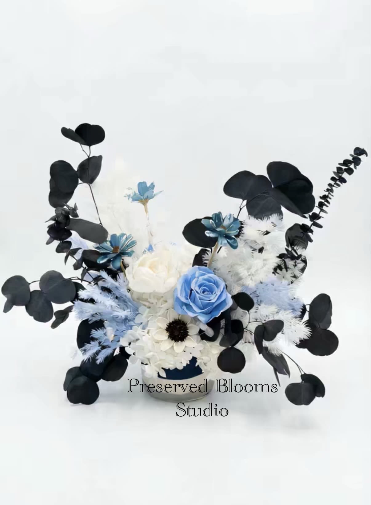 Asymmetrical arrangement of blue and white flowers with black foliage in a low container