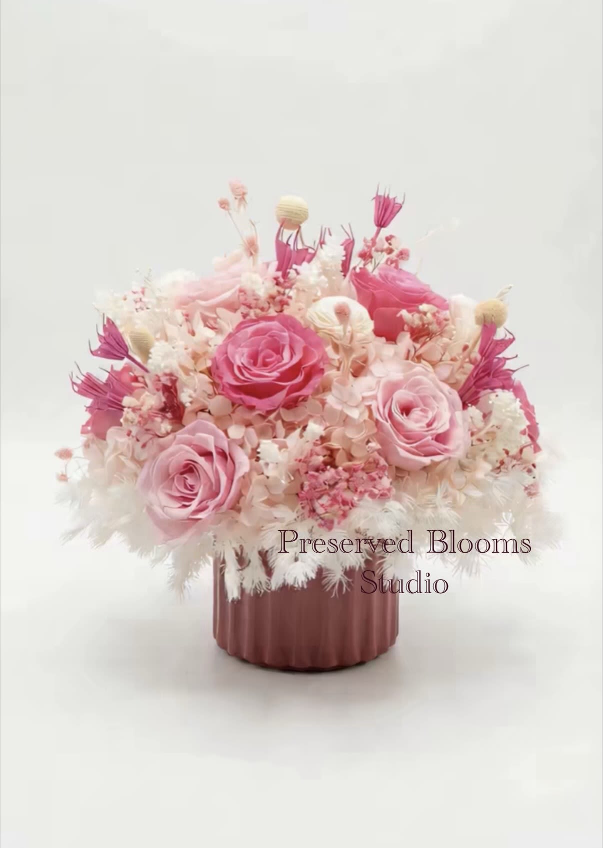 Low pink and white preserved flower arrangement with roses in a mauve ceramic pot