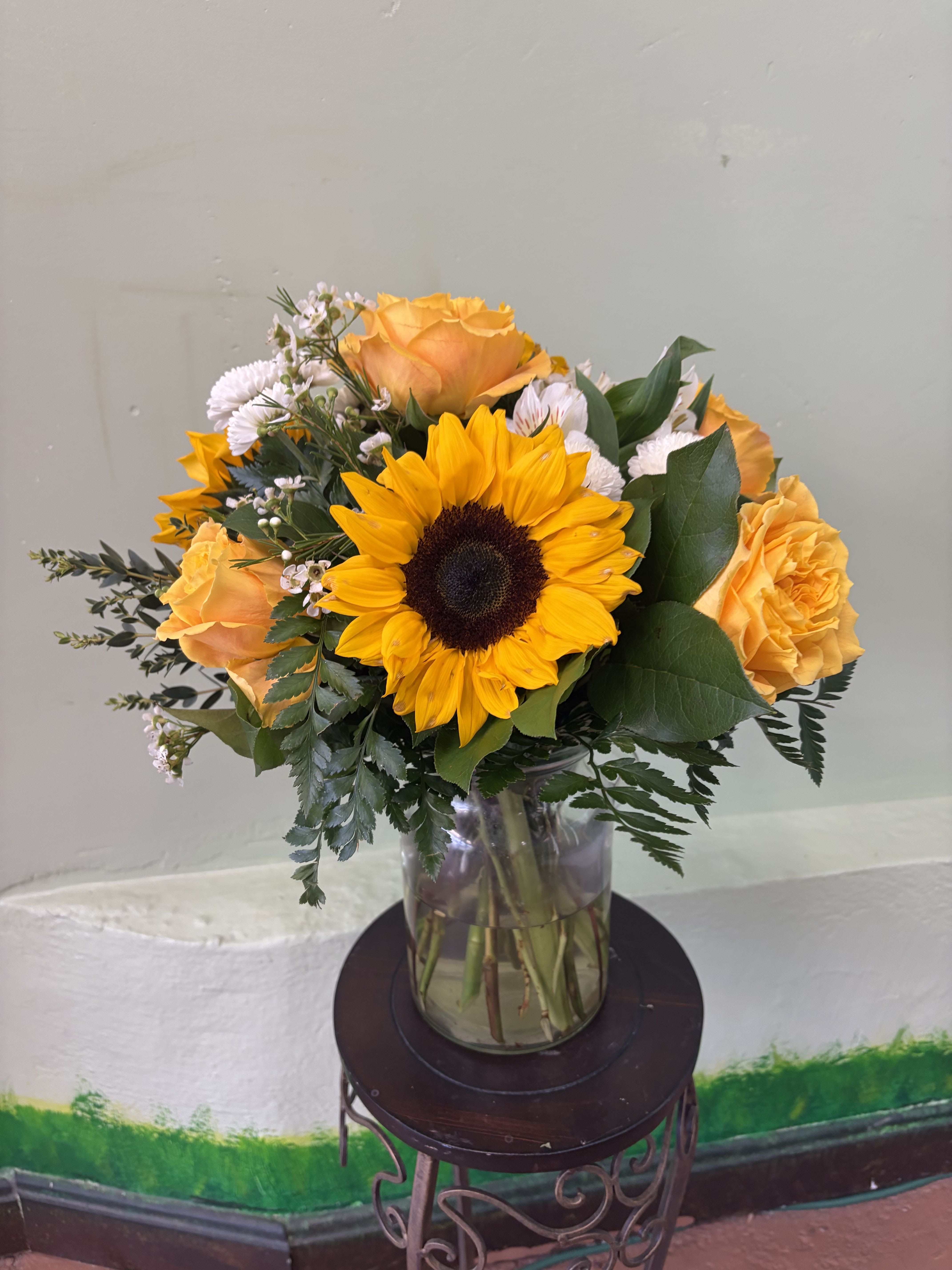 Sunny Glow Vase - A charming arrangement with bold golden hues and soft accents, arranged in a clear vase for a clean and elegant look.