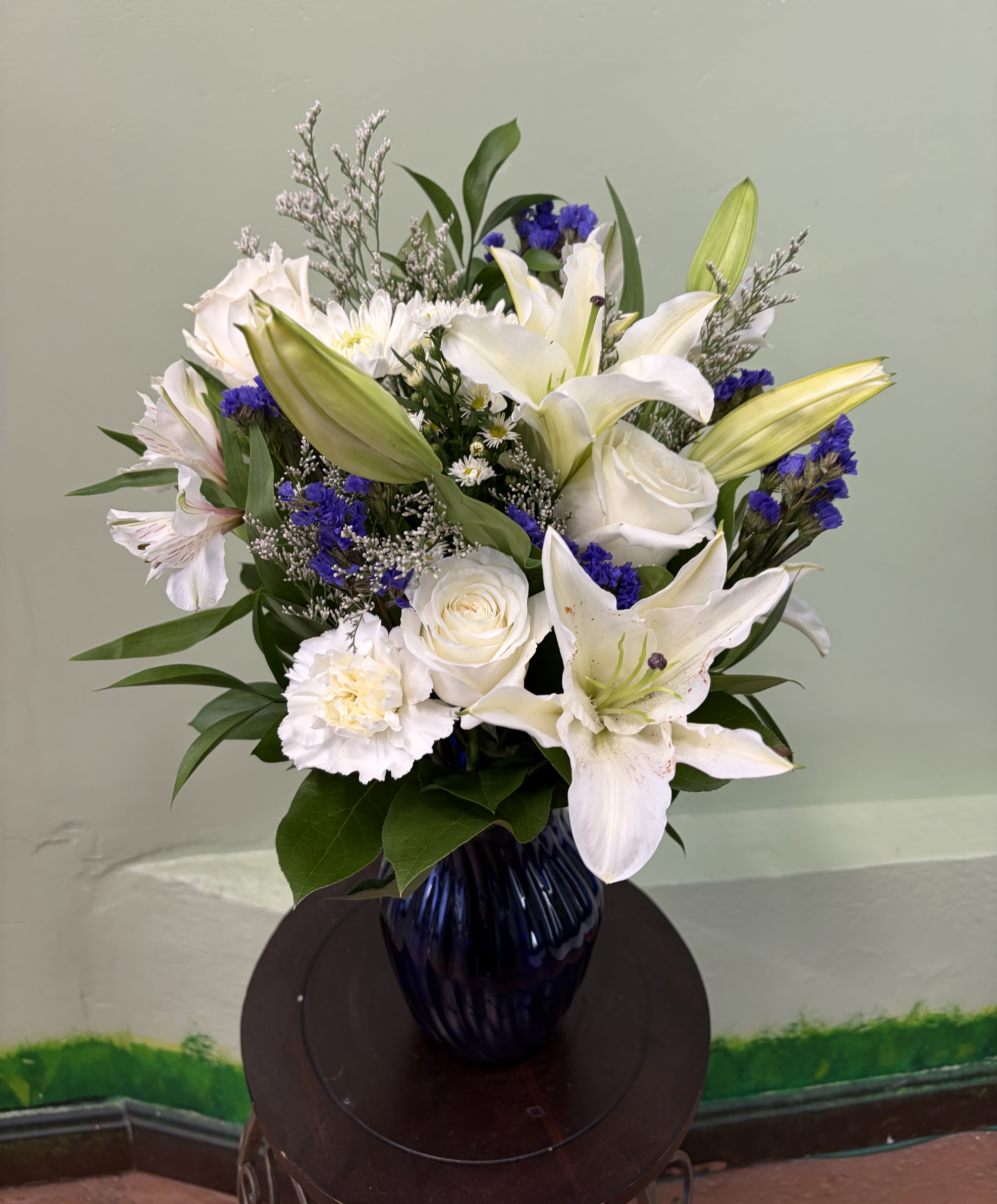 Elegant Ivory Bliss - A soft and graceful arrangement with creamy tones, delicate accents, and fresh greenery in a deep-toned vase for a refined look.