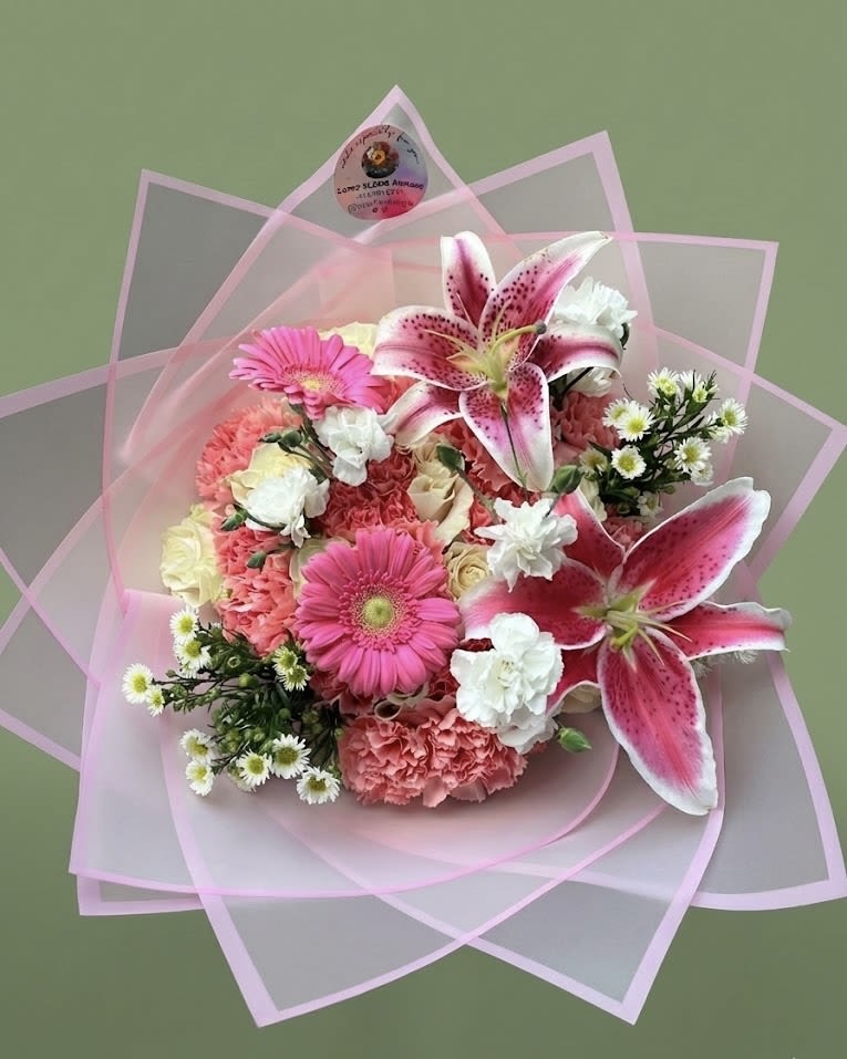 Hand-tied bouquet of pink lilies, gerbera daisies, carnations and white blooms in pink wrap