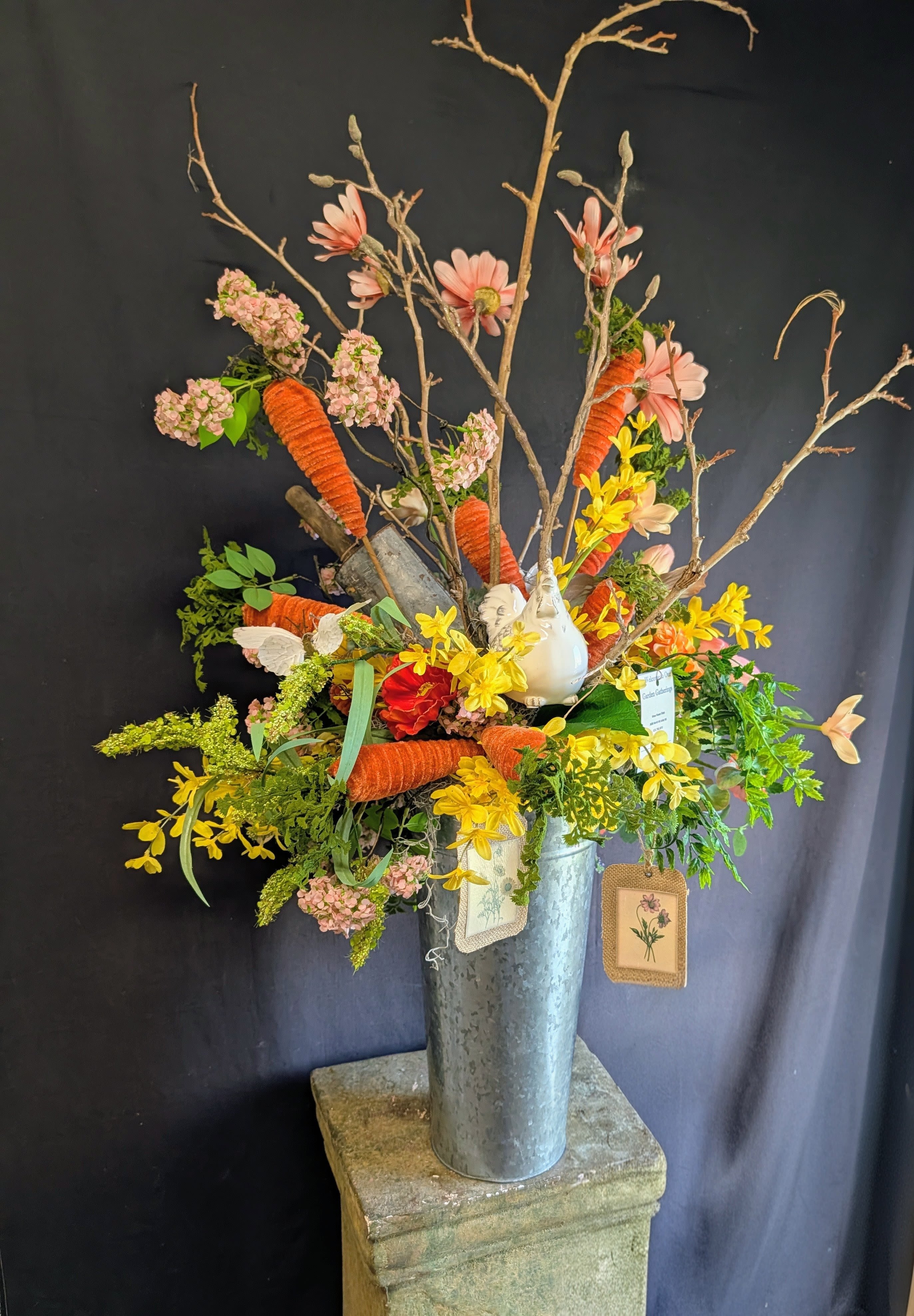SALE. Springtime Hen &amp; Garden Bloom Permanent Arrangement - Celebrate the season with a permanent botanical “garden” that never fades. This tall silver metal container is overflowing with colorful mixed blooms and playful spring accents, including two white ceramic chickens, whimsical felt carrots, delicate butterfly accents, and a rustic garden metal scoop. Designed for hearths, entryways, and statement spaces, it’s a charming spring and Easter décor piece that brings fresh‑from‑the‑garden joy to your home year after year.