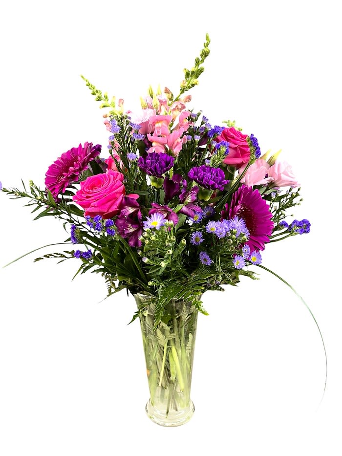 Tall mixed bouquet of pink roses and snapdragons with purple blooms in a clear glass vase