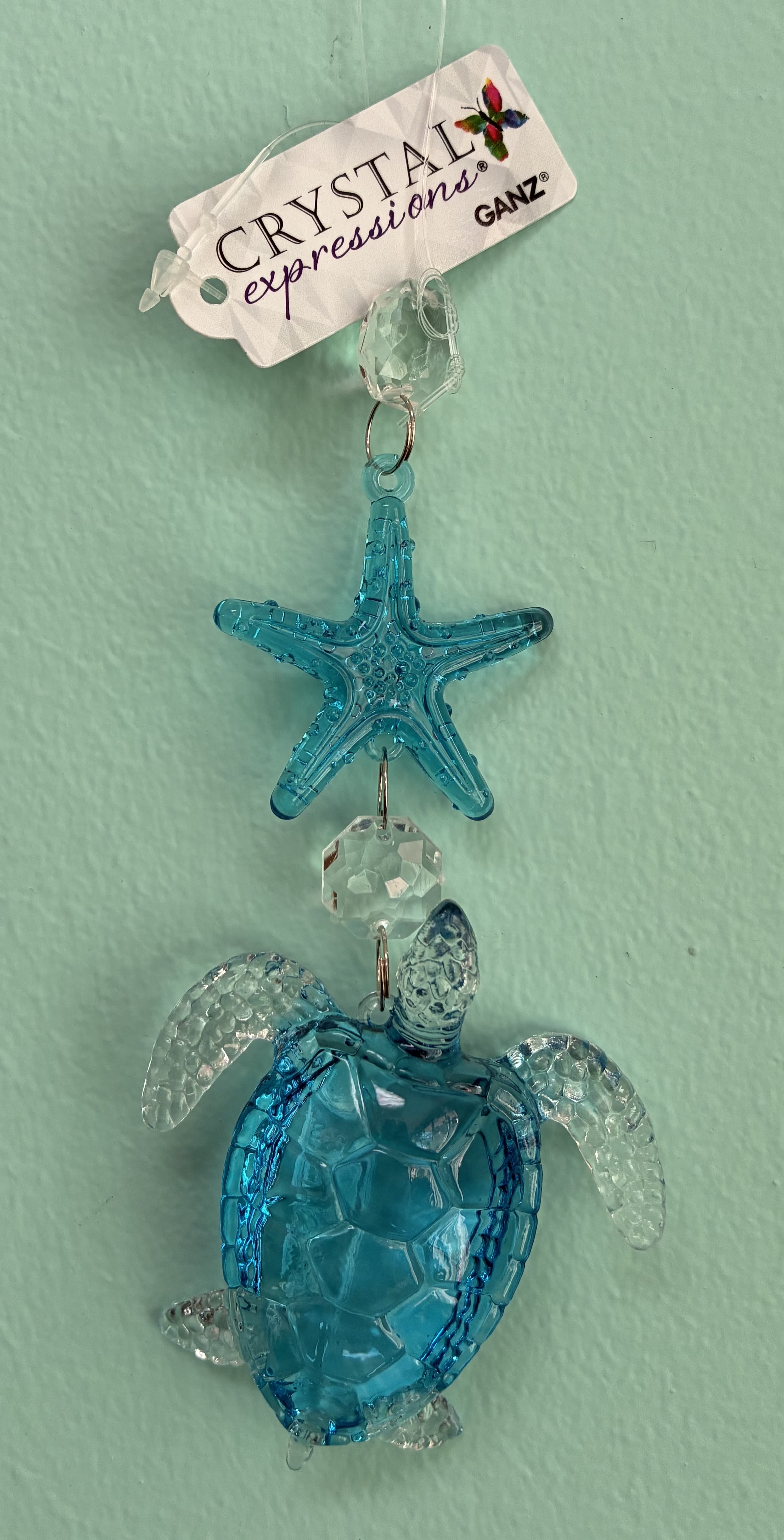 Blue crystal sea turtle and starfish hanging ornament with clear accents on a light aqua background