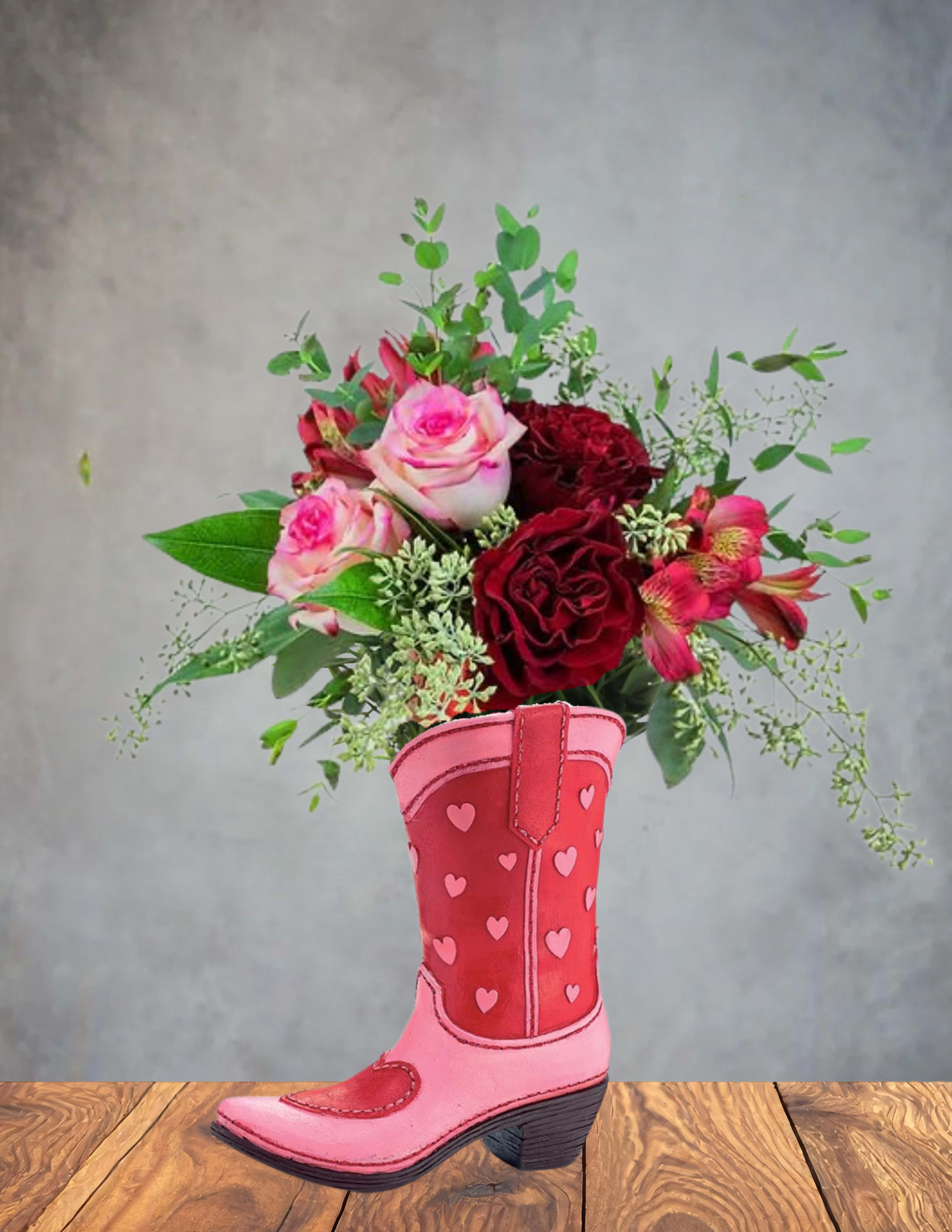 Pink and red roses with accent flowers in a heart-patterned pink cowboy boot vase