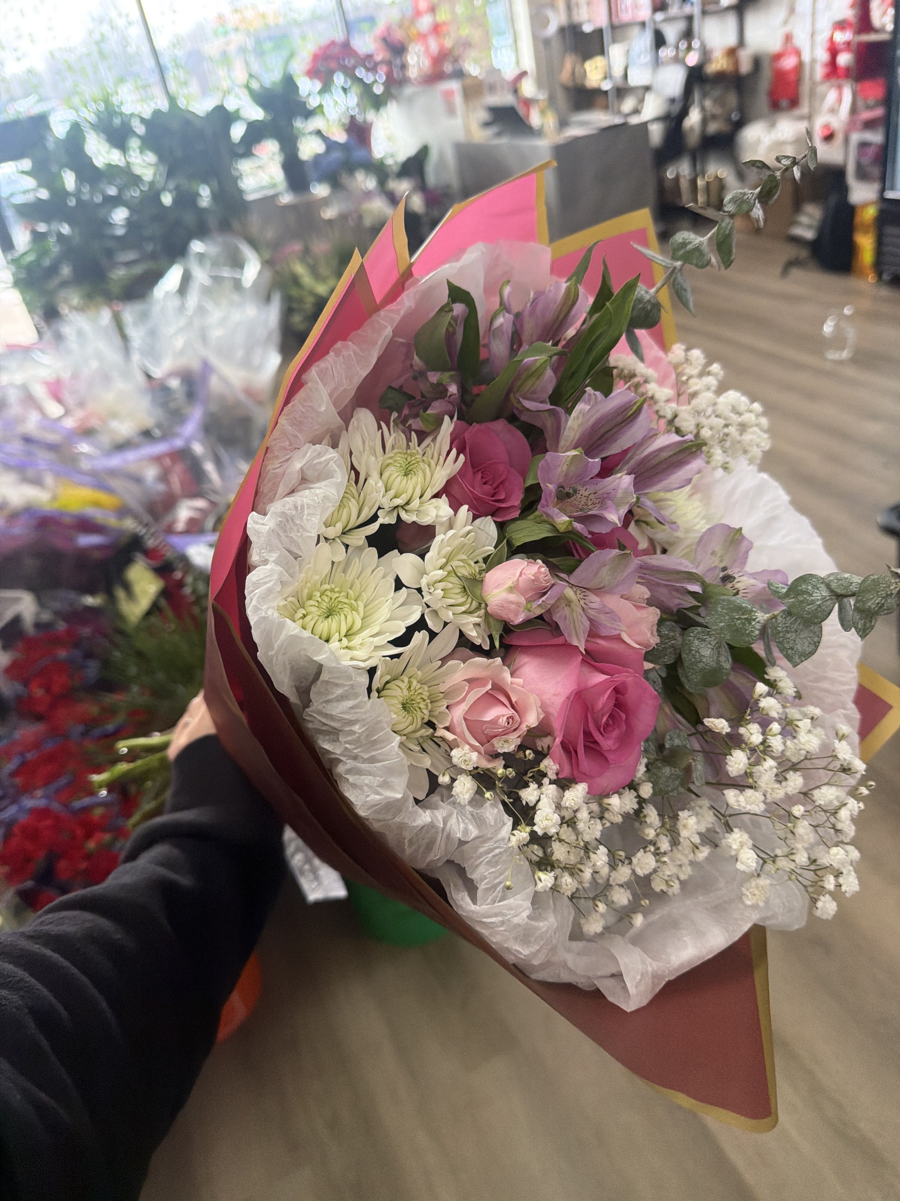 Hand-tied bouquet of pink roses, purple alstroemeria, white chrysanthemums and baby's breath in pink wrap