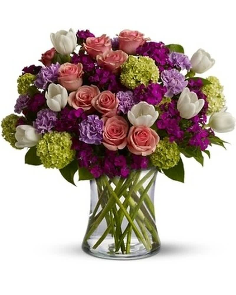 Mixed bouquet of pink roses, white tulips and purple flowers in a clear glass vase