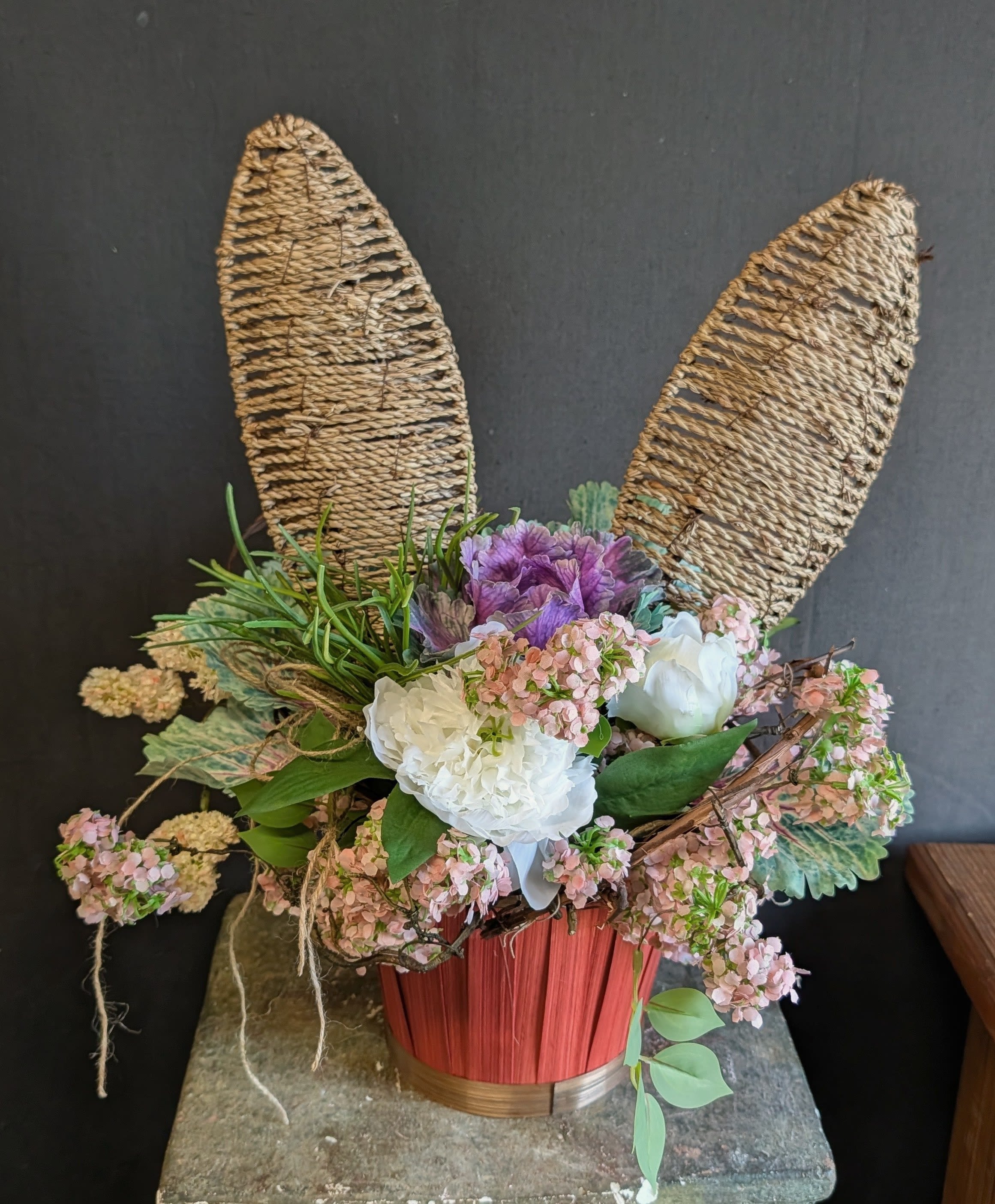 SLAE - Bunny Basket Blooms - A charming faux spring flower arrangement nestled in a rustic basket, topped with playful wicker bunny ears. This whimsical piece brings a touch of Easter magic and fresh spring color to your home—without any maintenance.