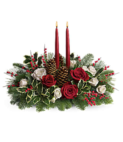 Low centerpiece of red and white roses with pine, holly, pinecones and two red taper candles