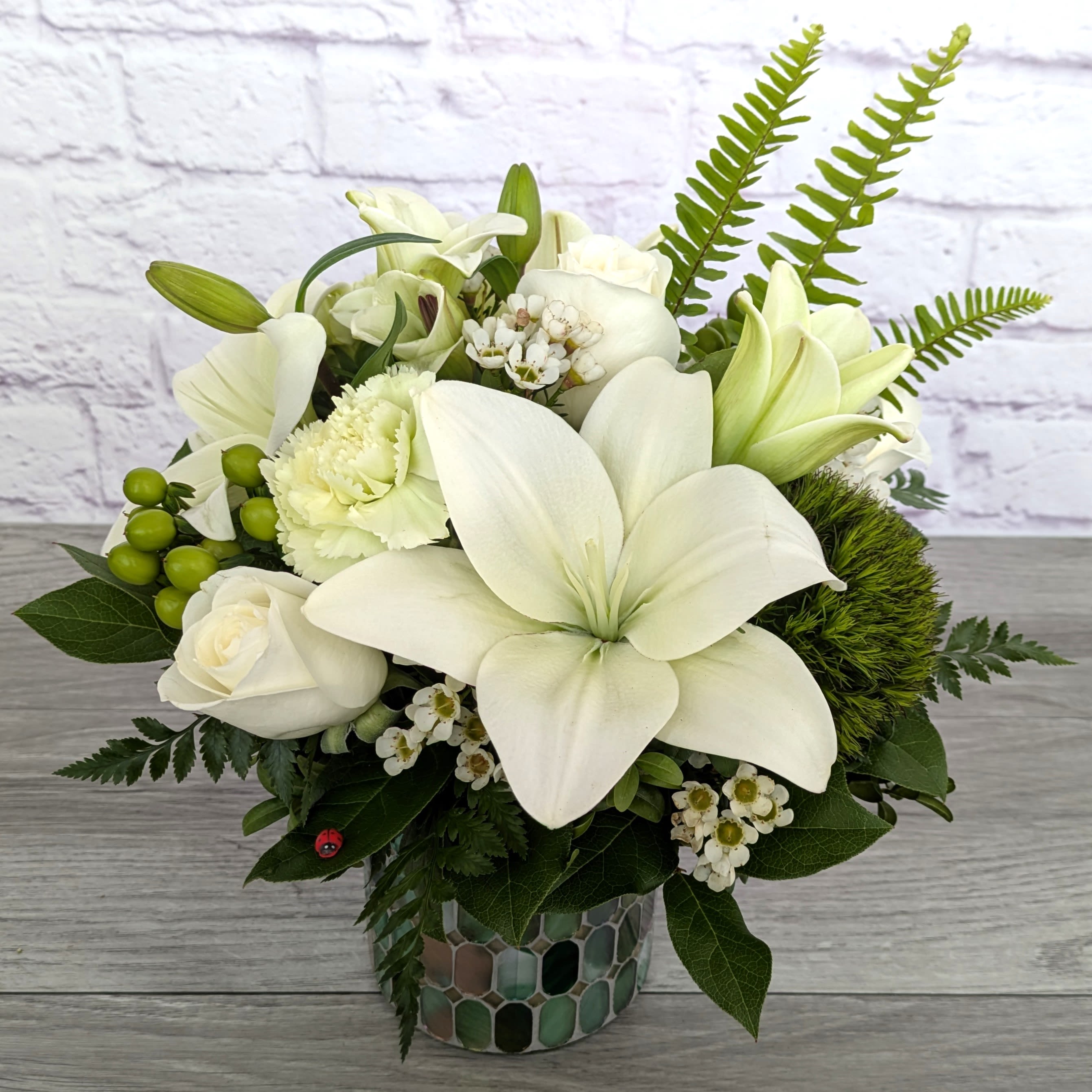 White lilies and roses arranged in a mosaic vase