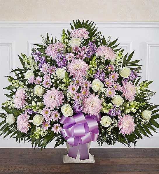Heartfelt Tribute Lavender &amp; White Floor Basket Arrangement - Floor basket arrangement of lavender daisy poms, football mums, and stock; white roses, snapdragons and monte casino; accented with soft, lush greenery Large arrangement measures approximately 34"H x 36"L Small arrangement measures approximately 32"H x 30"L Appropriate for the funeral home Our florists use only the freshest flowers available, so colors and varieties may vary