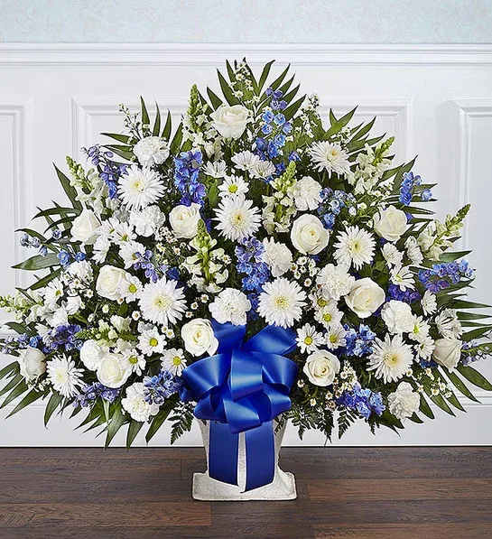 Heartfelt TributeBlue &amp; White Floor Basket Arrangement - Floor basket arrangement of blue delphinium; white roses, snapdragons, ceremonies, carnations, daisy poms and monte casino; accented with soft, lush greenery Large arrangement measures approximately 36"H x 42"L Medium arrangement measures approximately 34"H x 40"L Appropriate for the funeral home Our florists use only the freshest flowers available, so colors and varieties may vary