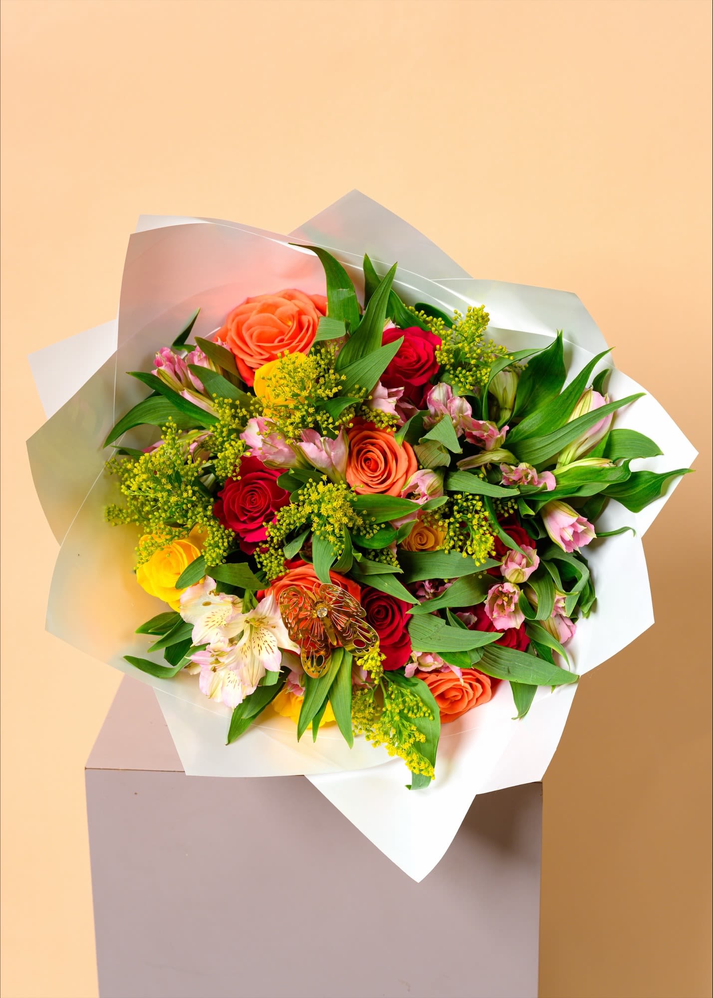 Sunset Garden Elegance Bouquet - A vibrant medley of orange and red roses, delicate pink blooms, and fresh greenery, artfully arranged to capture the warmth of a sunset garden. Accented with soft yellow fillers and a charming butterfly detail, this bouquet brings a lively yet graceful touch. Perfect for celebrations or heartfelt gestures, it radiates beauty, joy, and natural elegance.