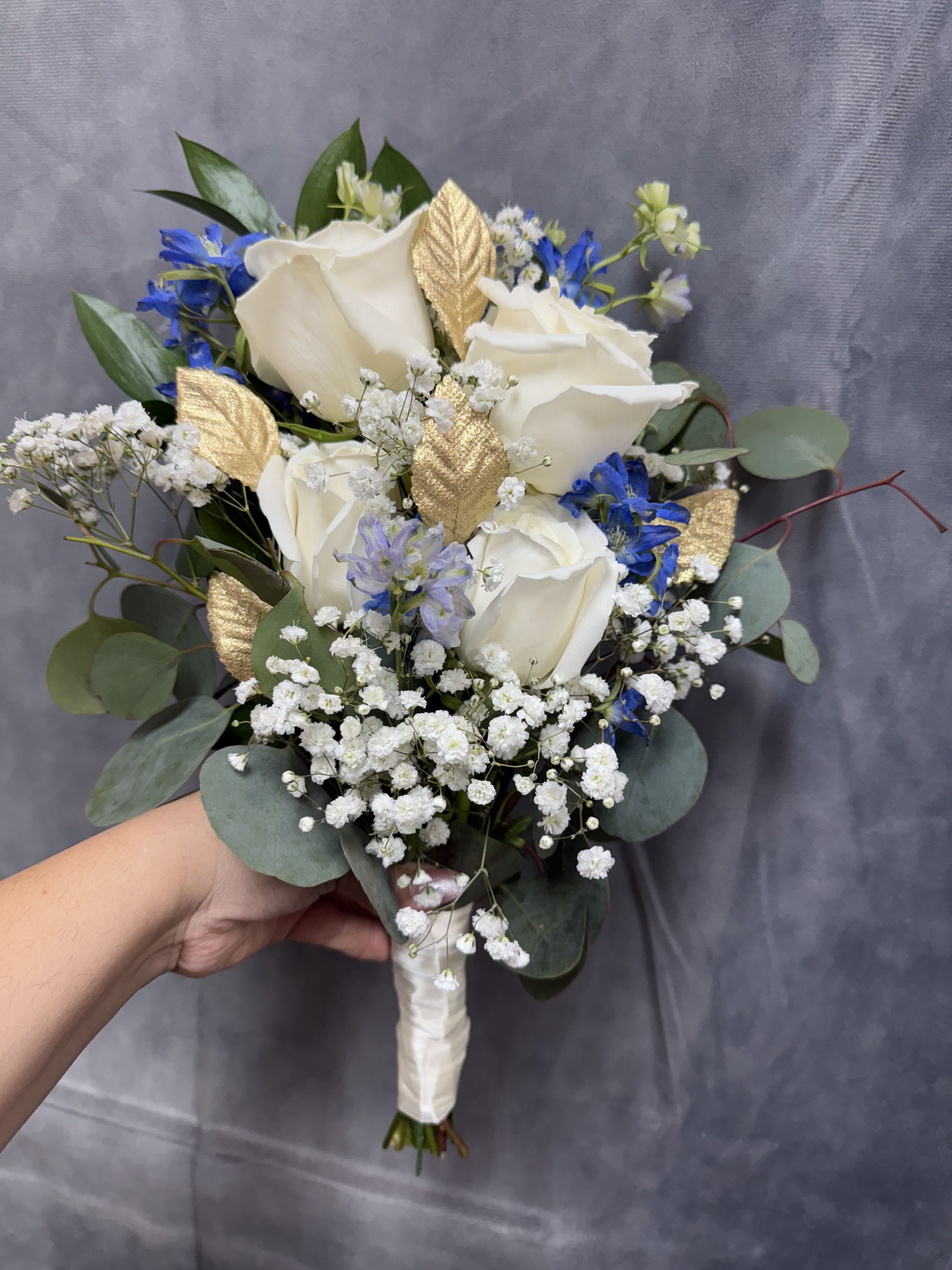 White gold blue prom bouquet  - Prom white gold and blue bouquet. Bouquet made with white roses ,  blue delphinium , baby breath and gold leaves 