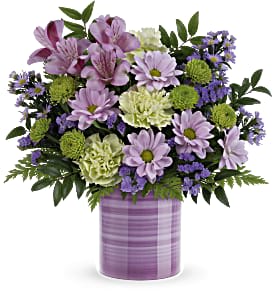 Lavender daisies, green mums, and pale carnations in a striped lavender ceramic cylinder vase