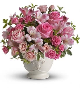 Pink roses and alstroemeria arranged in a white ceramic urn-style vase
