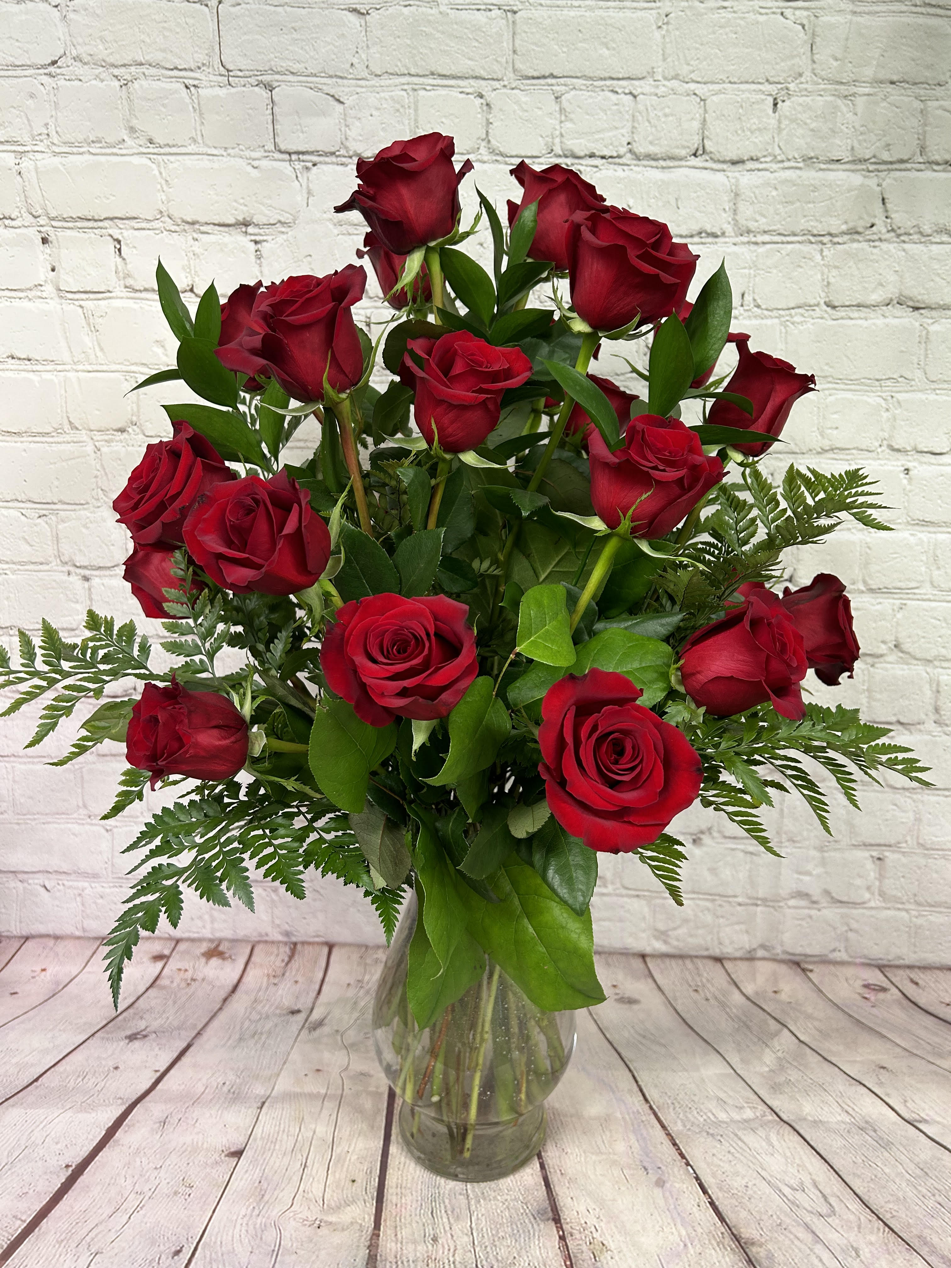 Tall arrangement of long-stemmed red roses in a clear glass vase