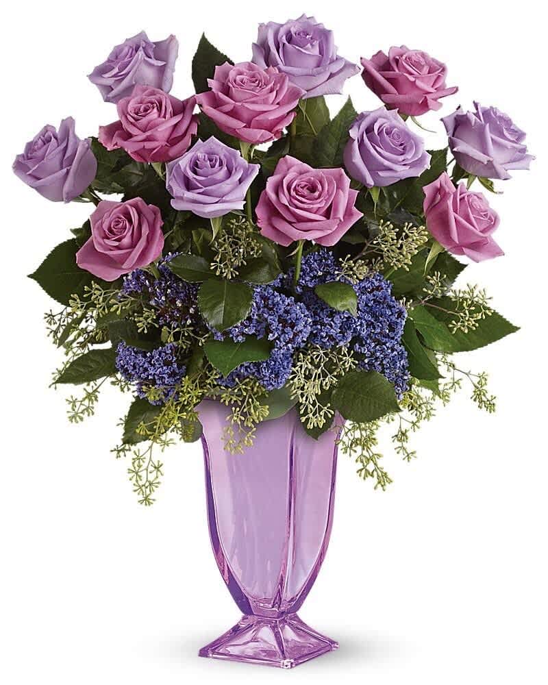 Tall arrangement of lavender and pink roses with purple filler flowers in a lavender glass vase