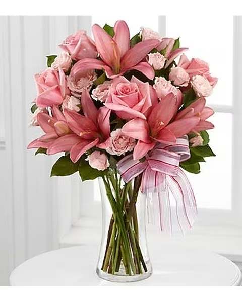 Perfect Poetry - This bouquet inspires and unites hearts with its stunning sweetness. Wonderfully elegant Stargazer Lilies stretch their petals across a bed of pale pink spray roses and seeded eucalyptus, brought together in a clear glass vase tied with a sheer pink ribbon around the neck, creating a bouquet that represents the unending bond that you will always share with your mother. Item display is Deluxe version.