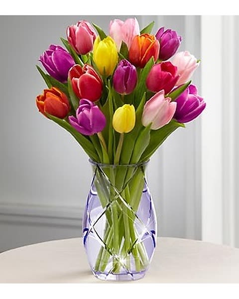 The Spring Tulip Bouquet by Better Homes &amp; Gardens - The Spring Tulip Bouquet by Better Homes and Gardens is the perfect way to celebrate the arrival of the spring months! An assortment of tulips in a stunning array of colors arrives presented in a designer etched purple glass vase to create a cheerful and charming bouquet your special recipient will love. 