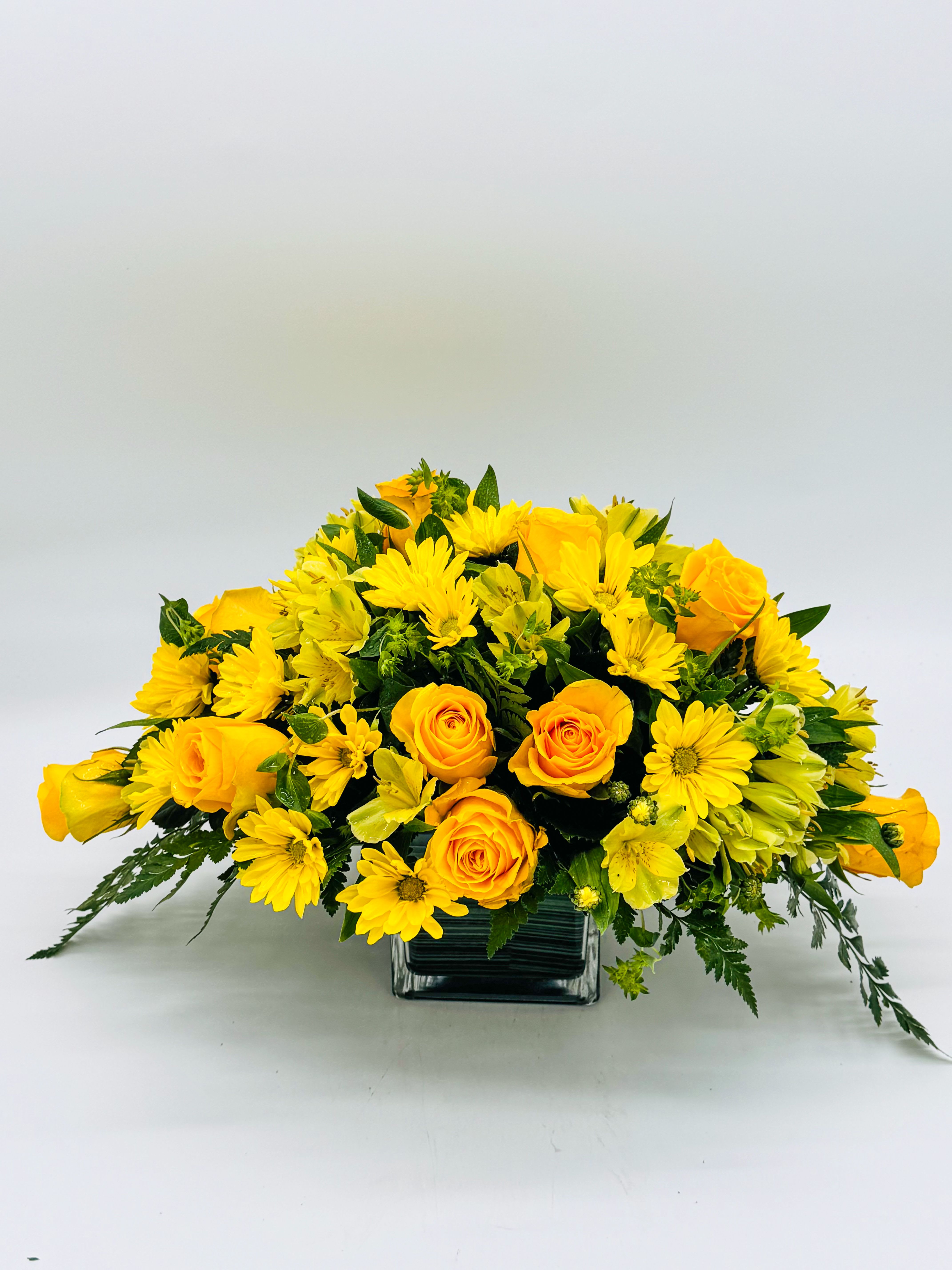 Golden Glow - A radiant explosion of pure sunshine—vibrant yellow roses, cheerful daisies, fluffy chrysanthemums, and delicate alstroemeria all tumble together in a sleek cube container,This bold, happy bunch brings instant warmth to any room, like a hug from summer itself. Perfect for birthdays, “just because,” or anyone who needs a little light.