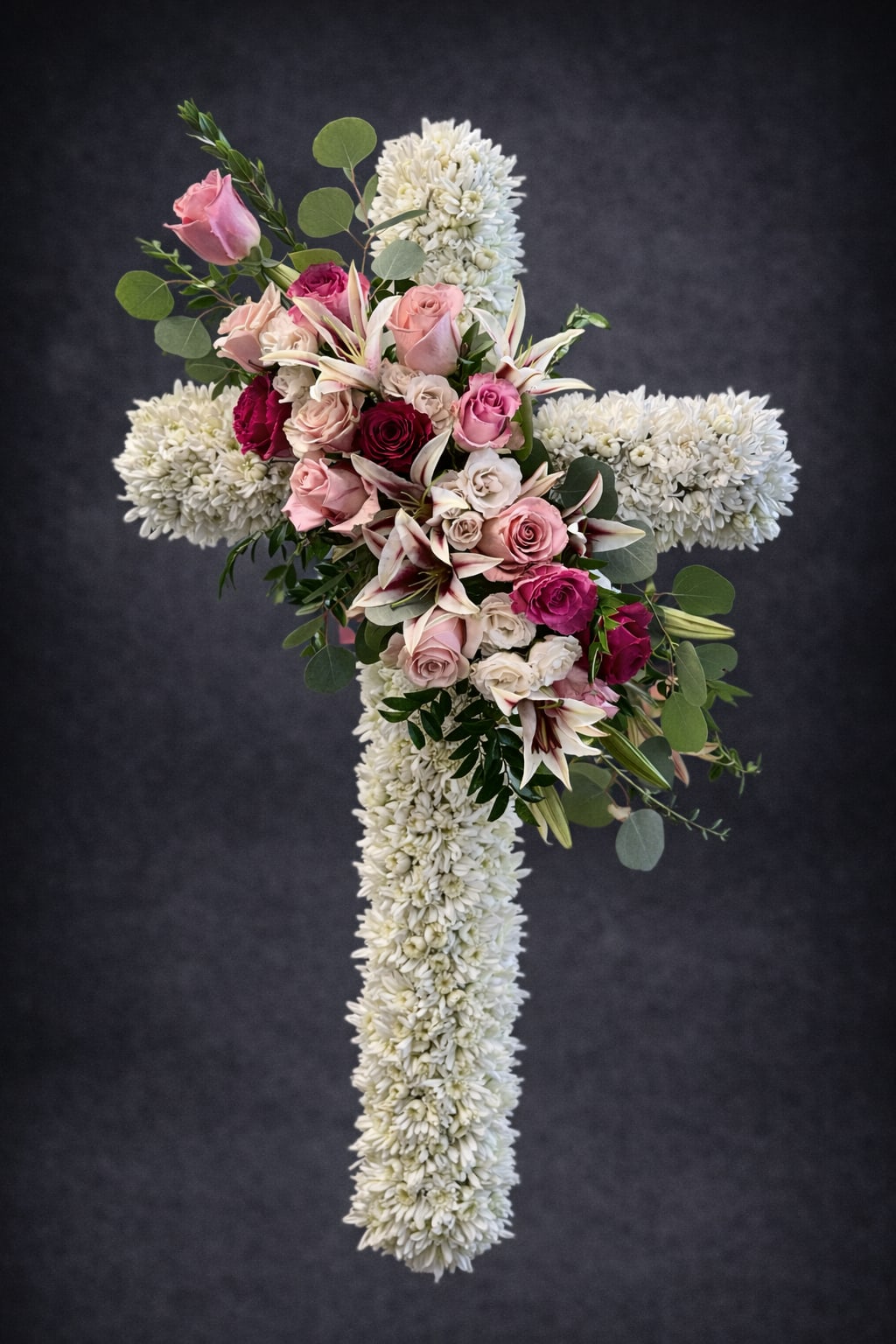 Sympathy Cross - A foam cross filled with white flowers, lined with greenery.  Red and white roses are designed diagonally on the center of the cross.  