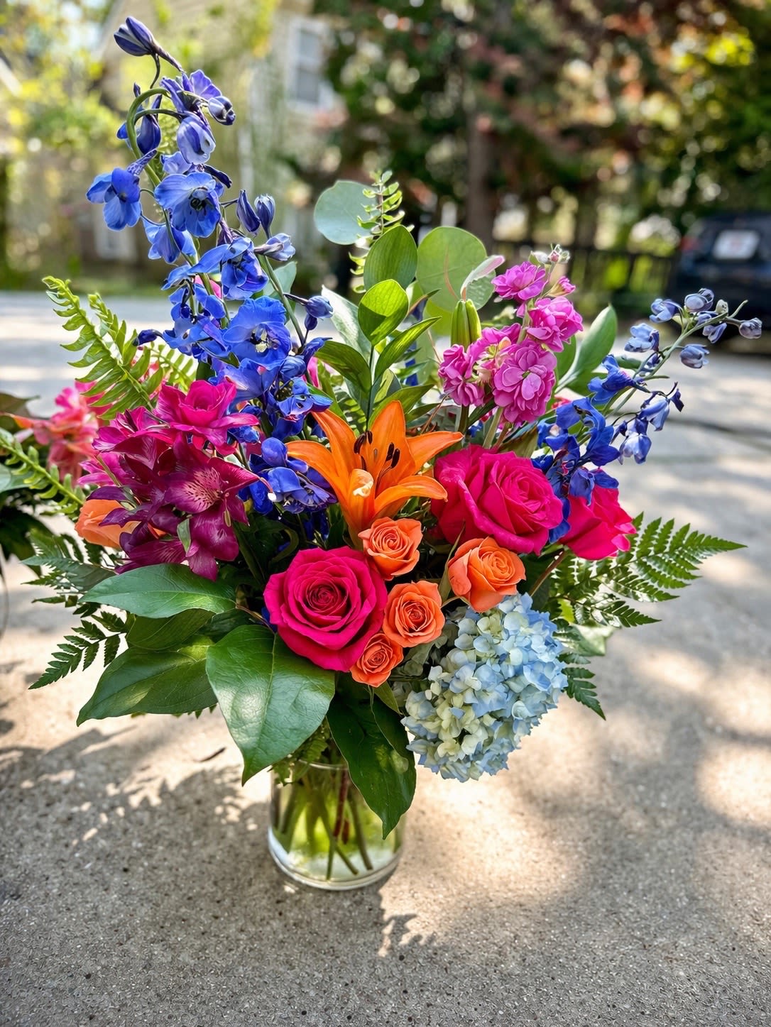 Vibrant Garden Mix Bouquet with Roses, Lilies &amp; Delphinium - Bring color and joy to any occasion with this Vibrant Garden Mix Bouquet, a stunning arrangement designed with a rich variety of fresh seasonal flowers.  This eye-catching design features bright pink roses, orange spray roses, a striking orange lily, tall blue delphinium, soft hydrangea, and accent blooms, all surrounded by lush greenery in a clear glass vase. The mix of bold colors and textures creates a lively, garden-inspired look that feels both elegant and full of energy.  Perfect for birthdays, celebrations, thank you gifts, or just because, this arrangement is designed to stand out and make a lasting impression.  Handcrafted with care by AZ Flowers &amp; Gifts LLC in Alpharetta, GA, each bouquet is made fresh and delivered with attention to detail.   Mixed seasonal premium flowers  Bright, colorful garden-style design  Clear glass vase included  Same-day delivery available in Alpharetta 30022  Designed by local florist AZ Flowers &amp; Gifts 