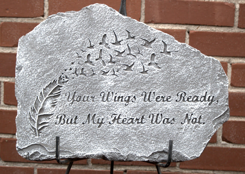 Gray stone memorial plaque with carved birds, a feather, and the inscription 'Your Wings Were Ready, But My Heart Was Not.'