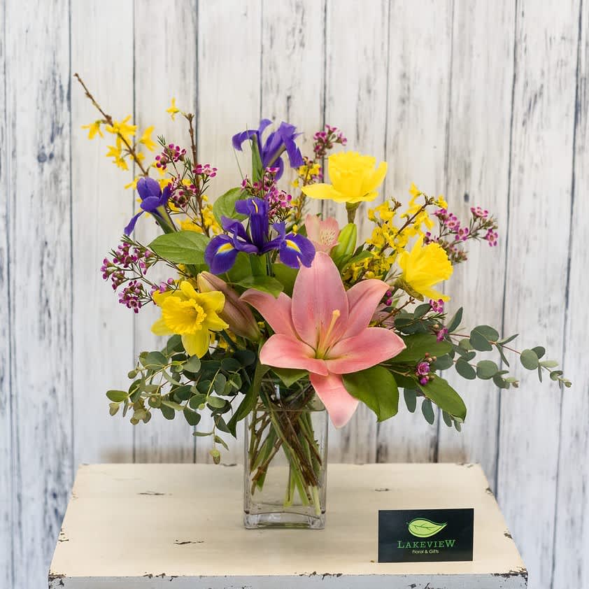 Ambiance - Spring seasonal blooms in a modern glass vase are perfect for a kitchen table. Includes Iris, Lily, Daffodil, and Forsythia.