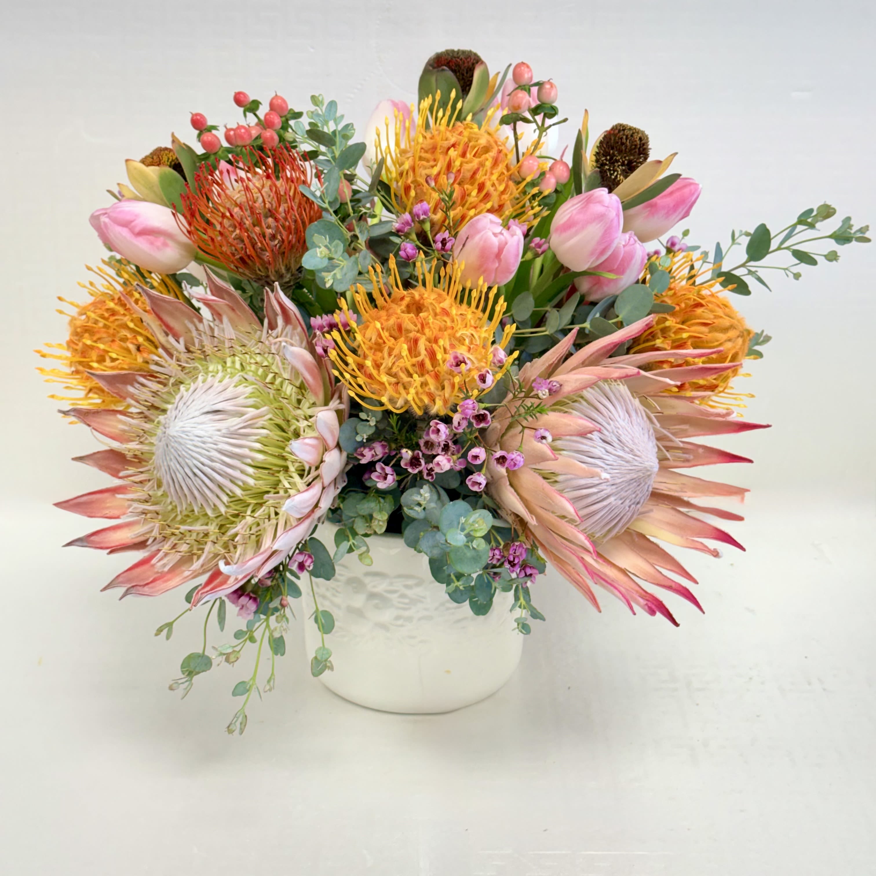Wild Elegance Bouquet  - A celebration of bold, artistic floral design featuring striking King Protea, vibrant Pincushion Protea, and delicate Tulips. This arrangement blends exotic textures, warm tones, and lush greenery to create a luxurious, nature-inspired centerpiece perfect for modern spaces and special occasions. 
