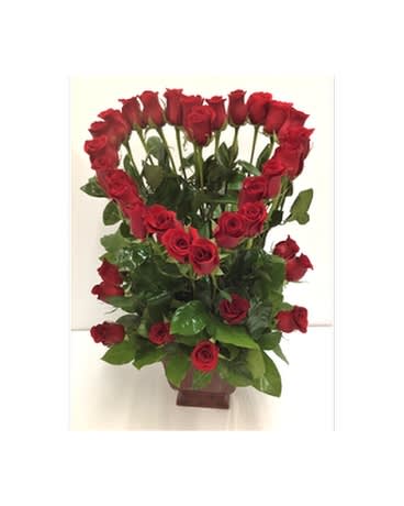 Tall arrangement of red roses shaped into a heart above more roses in a brown vase