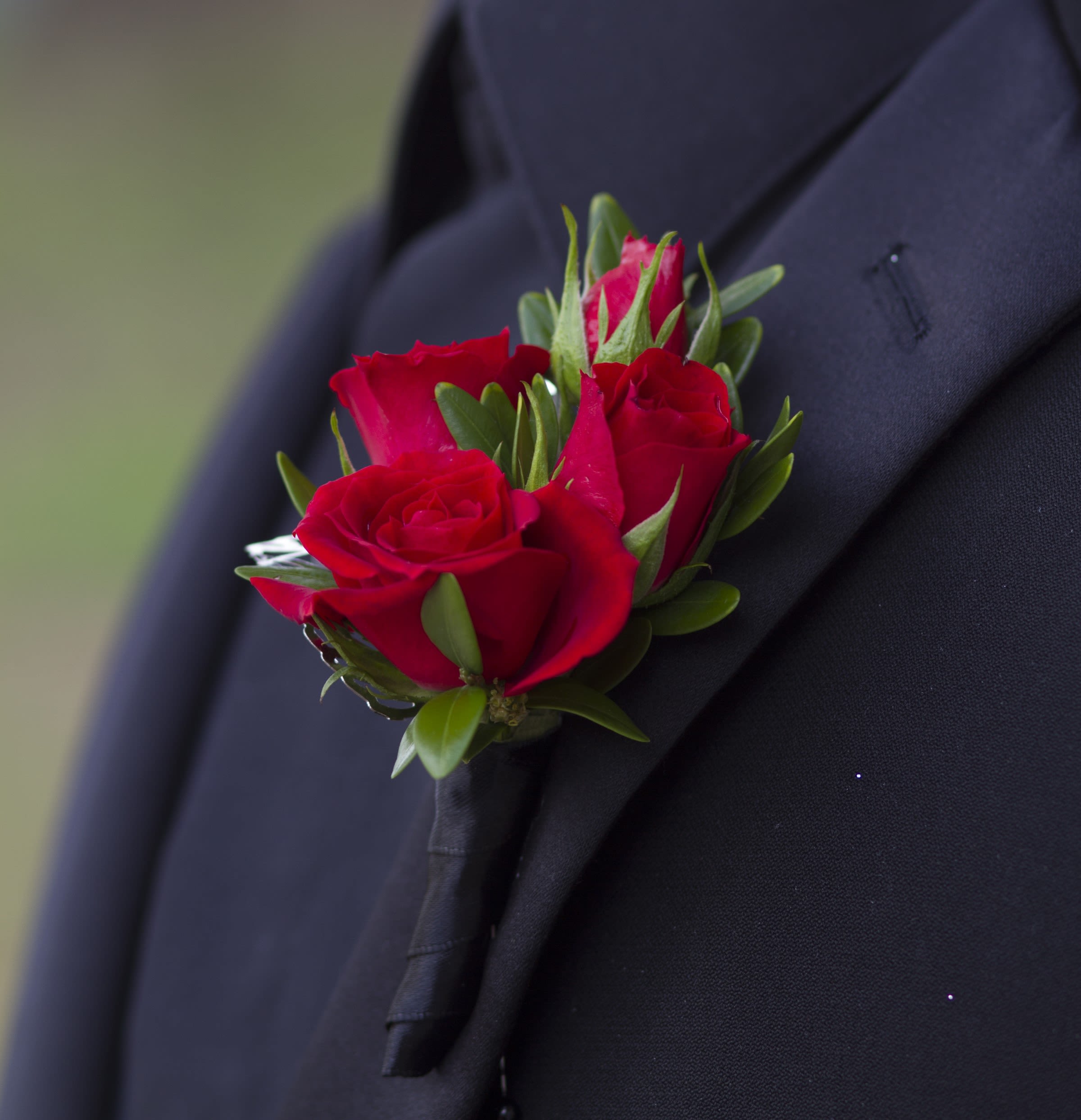 Small red rose boutonniere pinned to a black suit lapel
