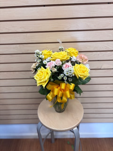 Bright Lacey - Mixed cut with yellow roses, white aster, white daisy, pink spray roses, and rose gold carnations in a vase