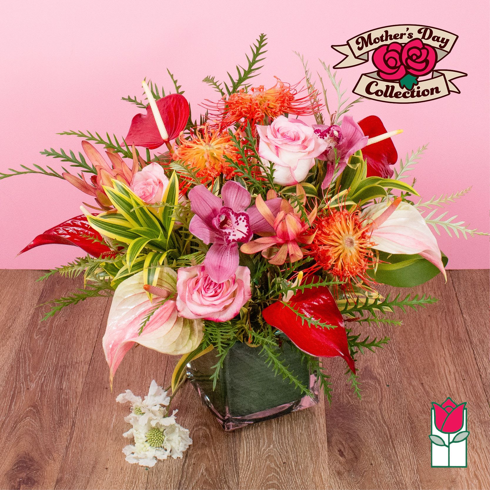 Tropical mixed bouquet with pink roses, orchids, red anthurium and protea in a square glass vase