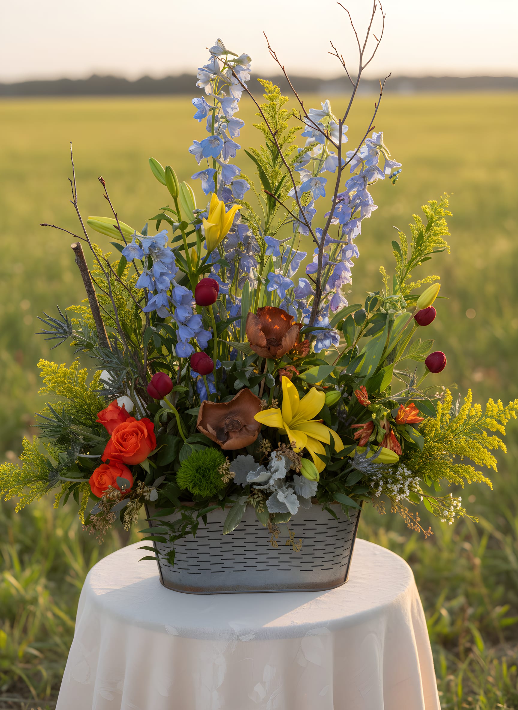 Lost in the Meadows (designers choice) - This photo is not AI generated. This is an actual design of ours. The backdrop has been substituted. The container will remain the same. Flower selection is subject to availability. If there are any requests please write them in the "special instruction".